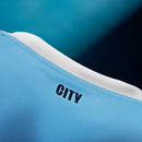Detalhe da camisa azul do Manchester City 25/26 com a palavra 'CITY' na parte de trás.