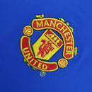 Emblema bordado do Manchester United em uma camisa azul retro.