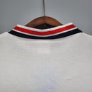 Detalhe da gola da camisa Manchester United Away 1985 Retro, com listras vermelhas e pretas.