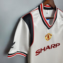 Camisa retrô do Manchester United Away 1985 com detalhes em preto e vermelho, modelo da Adidas.