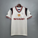 Camisa retrô do Manchester United Away 1985 com detalhes em preto e vermelho, logotipo da equipe e patrocinador SHARP.