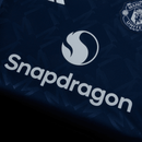 Camisa azul do Manchester United 24/25 com logo Snapdragon em destaque.