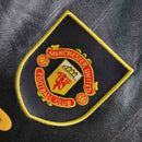Emblema da camisola Manchester United Away 93/95 Retro, com detalhes em amarelo e preto.