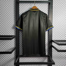 Camisola retro Manchester United Away 93/95, vista traseira, em tecido preto com detalhes amarelos e azuis.
