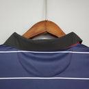 Detalhe da gola da camiseta Manchester United Away 99/00 Retro pendurada em cabide.