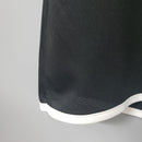 Detalhe da camisa retrô do Manchester United Home 00/02, mostrando tecido preto e acabamento em branco.