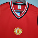 Camisa retro Manchester United Home 1985 com o logo do clube em destaque, ideal para fãs de futebol.
