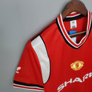 Camisa retrô do Manchester United de 1985, com detalhes em vermelho e branco, estilo clássico.