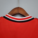 Detalhe da gola do jersey retro Manchester United Home 1985, destacando as cores vermelha e preta.