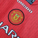 Camisa retrô Manchester United 1996 com detalhe do emblema e logo Umbro.