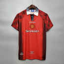 Camisa retrô do Manchester United Home 1996 com detalhes da marca Umbro e slogan Theatre of Dreams.