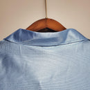 Camisolas Napoli Home 90/91 Retro, detalhe do colarinho em tecido azul, pendurada em cabide.