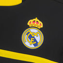 Escudo do Real Madrid em camisola de goleiro preta com detalhes em amarelo da coleção 11/12 retro.