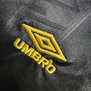Logo da Umbro em dourado em tecido preto, parte da camisola Manchester United Away 93/95 Retro.